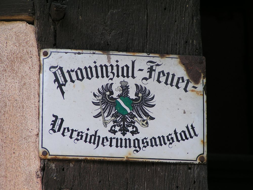 Historický emailový štít nemeckej požiarnej poisťovne na hrázdenom tráme
